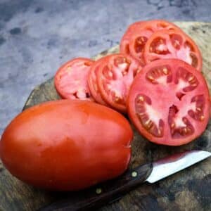 Comstock Sauce and Slice tomatoes on a wooden cutting board.